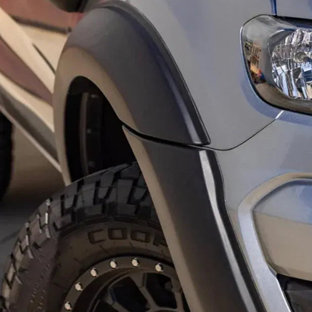 Close-up of a vehicle's headlight and fender with a blurred background